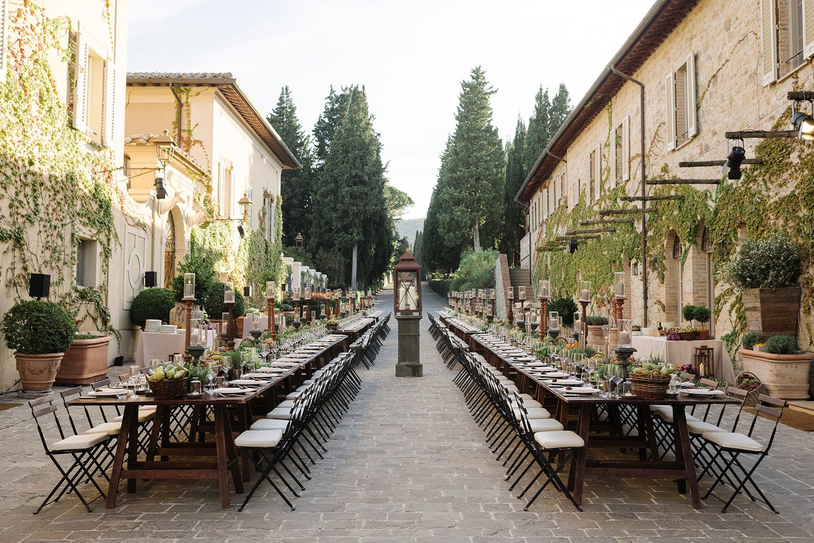 Couple at a long wedding table in a cypress-lined courtyard